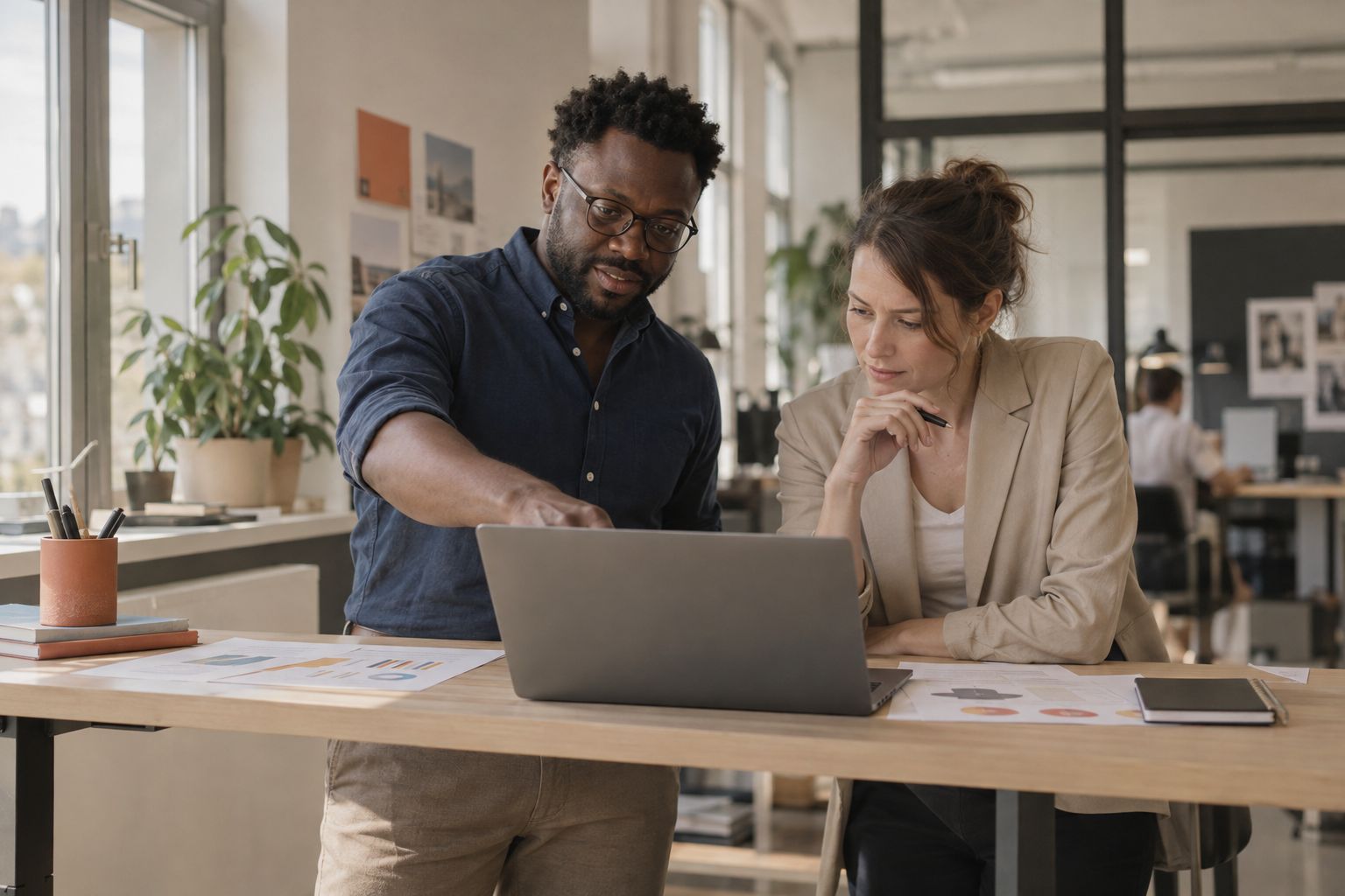 Marketingleiter und Kollegin besprechen etwas am Laptop